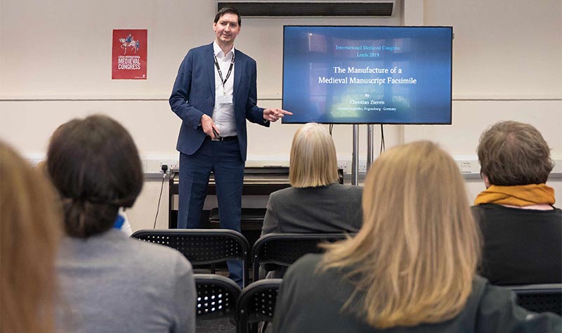 Internationale Vorträge vor Fachpublikum – hier: Christian Ziereis beim Vortrag "The Manufacture of a Medieval Manuscript Facsimile" beim International Medieval Congress an der University of Leeds, dem größten Mediävisten-Kongress der Welt